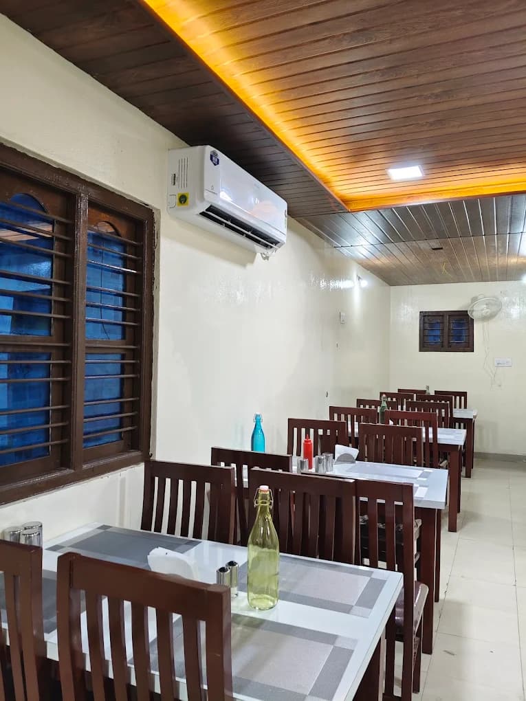Warmly lit dining room with wooden seating at Bharathi Kitchen